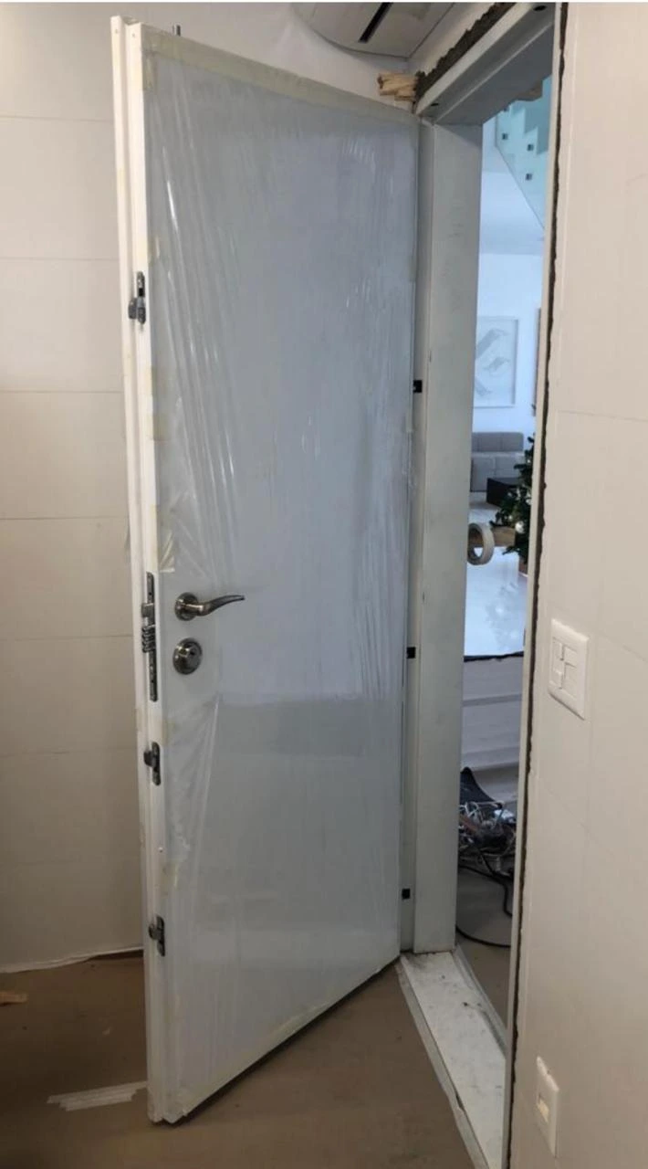 Porta blindada branca durante o processo de instalação, com múltiplas travas de segurança e estrutura interna em aço. Solução ideal para reforço em entradas residenciais.