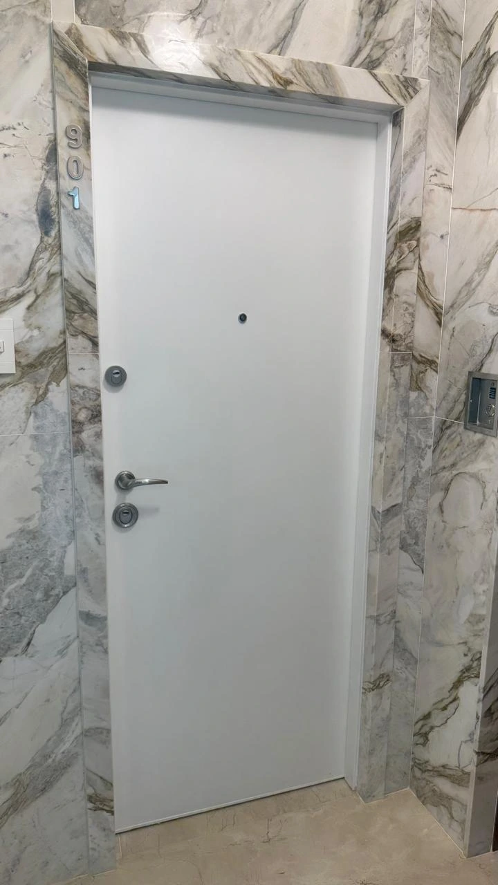 Porta blindada branca finalizada com múltiplas fechaduras e acabamento em mármore nobre. Ideal para apartamentos que exigem segurança reforçada sem abrir mão da estética refinada.